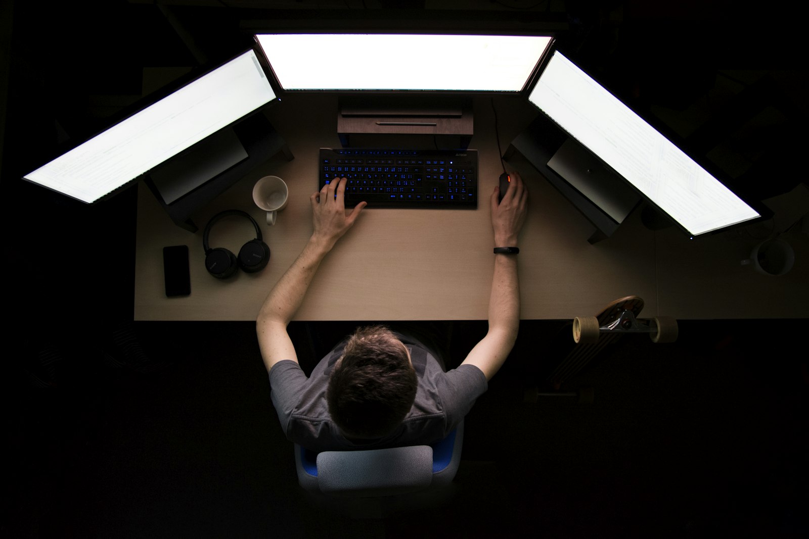 An overhead view of a desk with three monitors side by side